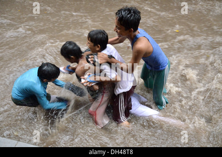 Jungs spielen in fließenden Monsun Regenwasser auf Straßen von Jodhpur Rajasthan Indien Stockfoto