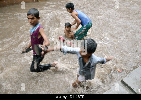 Jungs spielen in fließenden Monsun Regenwasser auf Straßen von Jodhpur Rajasthan Indien Stockfoto