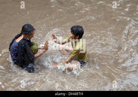 jungen und Mädchen spielen im fließenden Wasser des Monsuns Jodhpur Indien Stockfoto