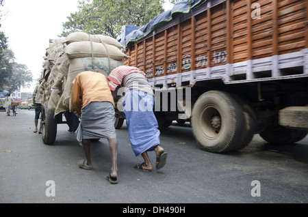 Arbeitnehmer, die Hand drücken Warenkorb Arbeiter tragen riesige Gepäck Kolkata Westbengalen, Indien Stockfoto