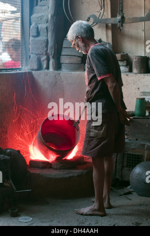 Mann stehend und Heizung Kupfergefäß in brennenden Brennofen Pune Maharashtra Indien Asien Nein Herr Feb 2012 Stockfoto