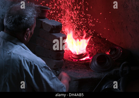 Man Heizung Kupfergefäß in brennenden Ofen, Pune Maharashtra Indien Asien Stockfoto