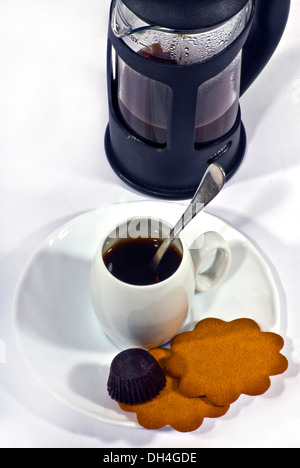 Kaffee, traditionelle französische Presse Kaffeemaschine und kleine weiße Tasse mit einem silbernen Löffel, Kekse und Schokolade. Stockfoto