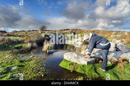 Eine Frau Wanderer stoppt, um ihre Schnürsenkel binden auf Bodmin Moor in Cornwall Stockfoto