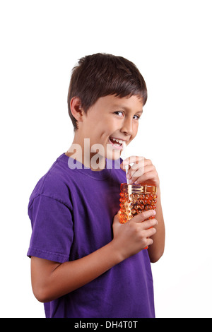 Kleiner Junge trinken aus orange Glas auf weißem Hintergrund Stockfoto