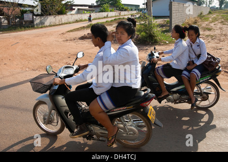 Horizontale Porträt von Schulkindern auf Mopeds, die nach der Schule nach Hause fahren. Stockfoto