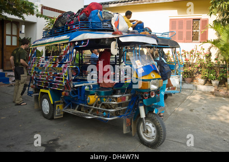 Horizontale Nahaufnahme von einem Jumbo Tuk-Tuk mit Rucksäcken auf dem Dach in Luang Prabang geladen wird. Stockfoto