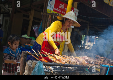 Horizontale Porträt von einem lokalen Lao-Dame und ihrer Tochter Grillen Spieße auf einem Grill an einer Raststätte. Stockfoto