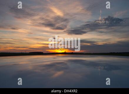 Eines, Deutschland. 19. Oktober 2013. Der Abendhimmel mit dem Sonnenuntergang spiegelt sich in einem Autodach auf einem Feld in eines, Deutschland, 19. Oktober 2013. Foto: Patrick Pleul/ZB/Dpa/Alamy Live News Stockfoto