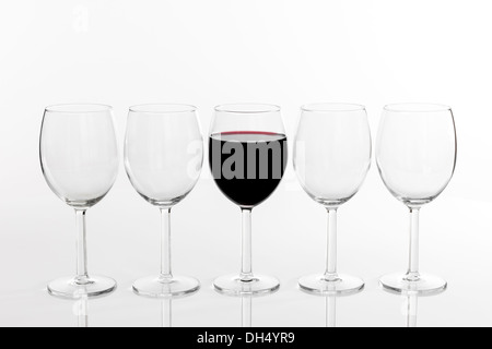 Glas Rotwein in einer Reihe von leeren Gläser auf weißem Hintergrund. Stockfoto