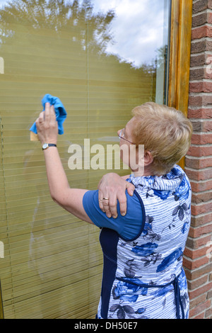 Frau mit Gelenkschmerzen in Schulter ein Fenster Reinigung Stockfoto