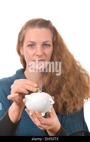 Frau, eine 2-Euro-Münze in ein Sparschwein Stockfoto