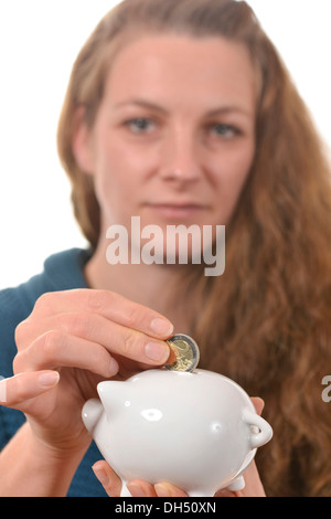 Frau, eine 2-Euro-Münze in ein Sparschwein Stockfoto