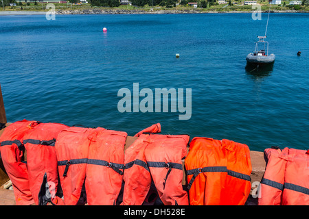 Rote Life preservers sitzen über ein Geländer trocknen in der Sonne mit Blick auf einen schmuddeligen vor Anker in der Bucht. Stockfoto