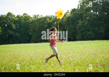 Mädchen auf einer Wiese mit einem Windrad laufen Stockfoto