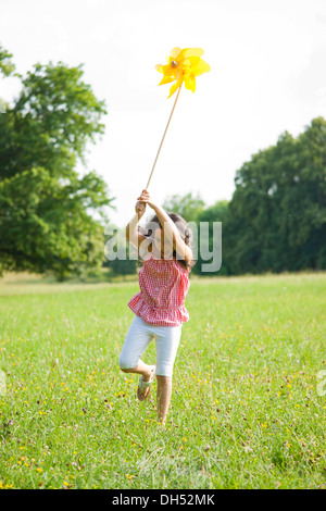 Mädchen auf einer Wiese mit einem Windrad laufen Stockfoto