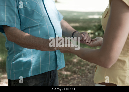 Eine Frau und ein älterer Mann halten einander die Hände Stockfoto