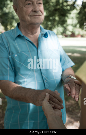 Eine Frau und ein älterer Mann halten einander die Hände Stockfoto