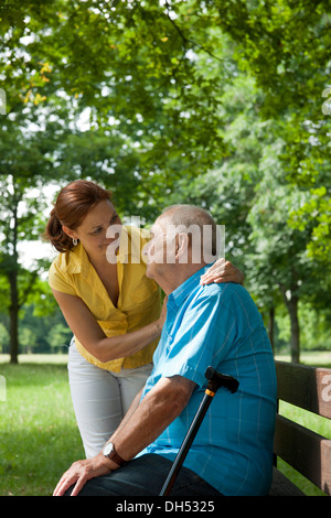 Frauen auf der Suche nach ein älterer Mann sitzt auf einer Bank in einem park Stockfoto