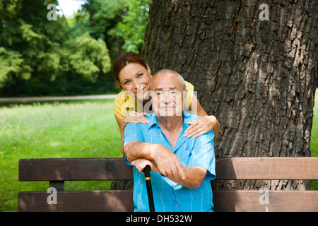 Frauen auf der Suche nach ein älterer Mann sitzt auf einer Bank in einem park Stockfoto