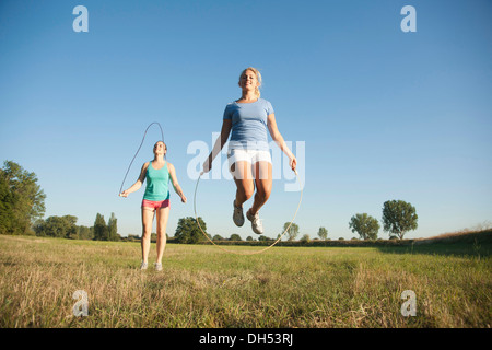 Zwei junge Frauen, die Seilspringen auf einer Wiese Stockfoto