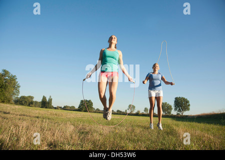 Zwei junge Frauen, die Seilspringen auf einer Wiese Stockfoto