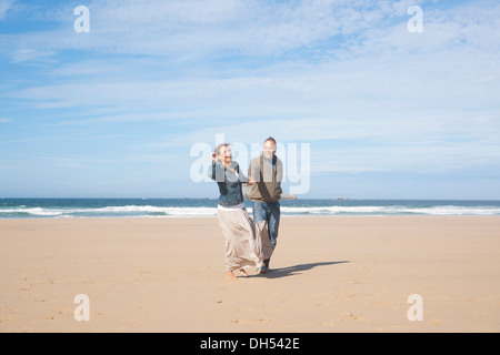 Paar am Strand entlang spazieren Stockfoto