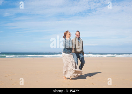 Paar am Strand entlang spazieren Stockfoto