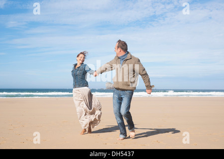 Paar am Strand entlang spazieren Stockfoto