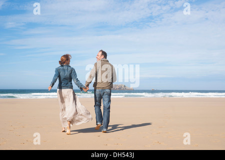 Paar am Strand entlang spazieren Stockfoto