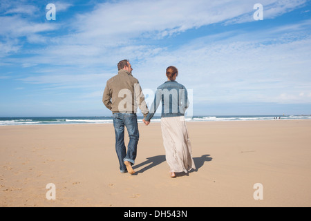 Paare, die an einem Strand entlang Stockfoto
