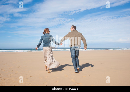 Paare, die an einem Strand entlang Stockfoto