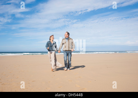 Paare, die an einem Strand entlang Stockfoto