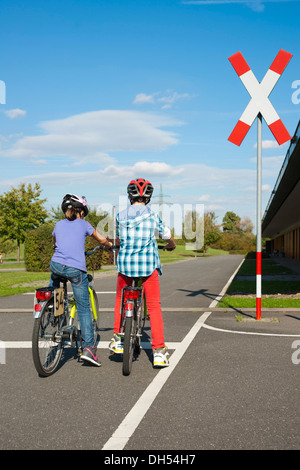 Kinder warten mit ihren Fahrrädern vor einem Bahnübergang bei einem Verkehrs-Bewusstsein-Kurs Stockfoto