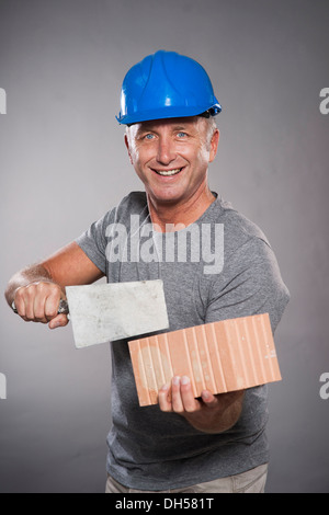 Bauarbeiter mit harten Hut, hält eine Kelle und einem Ziegelstein, Mannheim, Baden-Württemberg, Deutschland Stockfoto