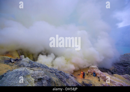 Schwefel-Bergleute Bergbau Schwefel am Ijen Vulkan mit Kratersee des Ijen an der hinteren, Kawah Ljen, Ost-Java, Java, Indonesien Stockfoto