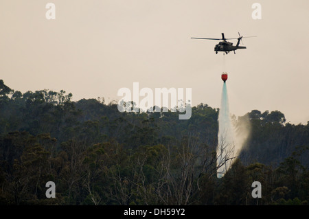 Ein UH-60 Black Hawk, 25. Aviation Regiment, 2nd Battalion, 25. Infanterie-Division, 25. Combat Aviation Brigade zugewiesen Tropfen 500 Gallonen Wasser auf ein Buschfeuer Okt. 24, während der Arbeit mit anderen Diensten und vertraglich Hubschrauber zum Löschen der Stockfoto