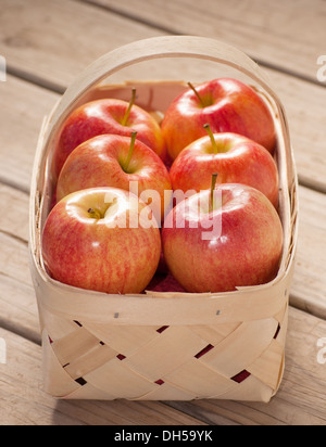 Äpfel in einem hölzernen geflochtenen Korb auf rustikalem Holzbrett Hintergrund Stockfoto