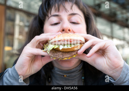 Junge Frau, die ein McDonlad Big Mac Essen Stockfoto