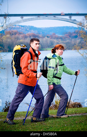 Paar an einem See vor einer Eisenbahnbrücke Wandern Stockfoto