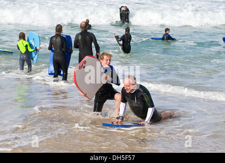 Vater und Sohn Bodyboard surfen im Meer am Strand in St. Ives Cornwall England UK Stockfoto