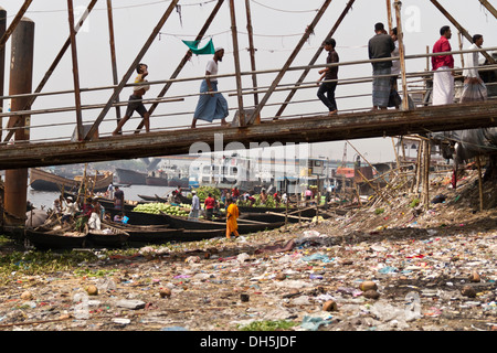 Ufer des Flusses Buriganga, Müll gefüllten Ufer Fußgänger überqueren eine Brücke zum Fährterminal, Dhaka, Bangladesch Stockfoto