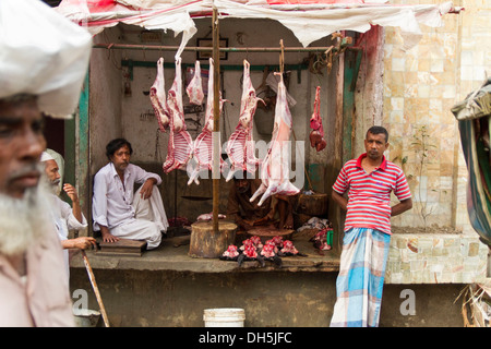 Am Straßenrand Schlachthof, hellhäutige Tiere hängen von Balken, rohes Fleisch unter, Metzger warten auf Kunden, Dhaka Stockfoto