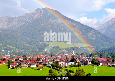 Blick über Oberstdorf mit einem Regenbogen vor Schattenberg Berg mit der Schattenberg-Schanze, Oberallgäu, Bayern Stockfoto