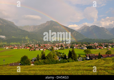 Blick über Oberstdorf mit Regenbogen, Schattenberg Berg mit Schattenberg-Schanze am Rücken, Landkreis Oberallgäu, Bayern Stockfoto