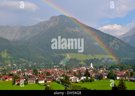 Blick über Oberstdorf mit Regenbogen, Schattenberg Berg mit Schattenberg-Schanze am Rücken, Landkreis Oberallgäu, Bayern Stockfoto