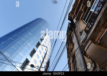 Bukarest, Rumänien. 23. Oktober 2013. Die moderne Glasfassade von der alten Bancorex Gebäude, einem alten Mietshaus und viele Kabel im Zentrum von Bukarest, 23. Oktober 2013. Foto: Jens Kalaene/Dpa/Alamy Live News Stockfoto