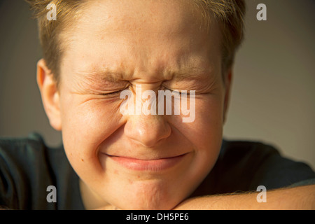 Zwölf Jahre alter Junge, schielen, seine Augen, die ersten Anzeichen einer Akne im Gesicht, Pubertät, Deutschland Stockfoto