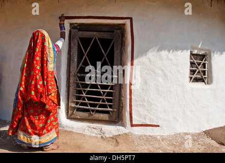 Junge indische Frau trägt einen traditionellen Sari oder Saree, malt ihre Haustür, Rajasthan, Indien, Asien Stockfoto