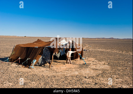 Junge Junge stand vor dem Zelt seine Nomadenfamilie, Steinwüste, Hamada, Erg Chebbi, Marokko, Marokko Stockfoto